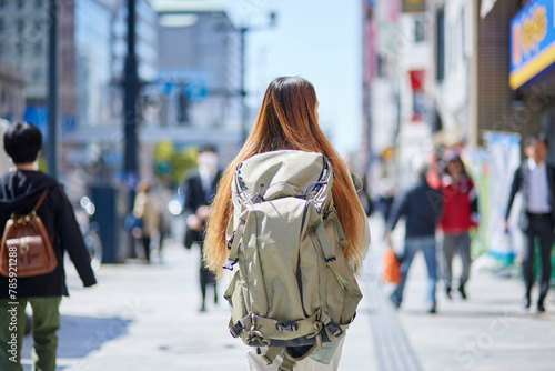 バックパックを背負って都会を歩く女性の外国人旅行者