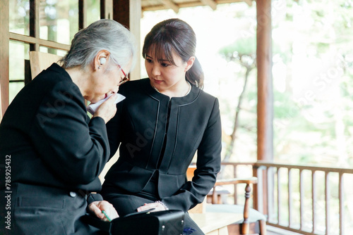 お葬式で泣く喪服を着た遺族の高齢者女性と若い日本人女性 