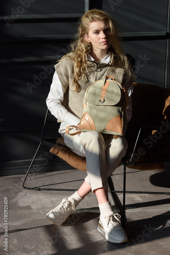 beautiful curly blond hair woman posing with a leather backpack