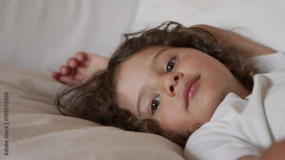 Young boy lying back on a white couch gazing at the camera in a relaxed pose Young boy lying back on a white couch gazing at the camera in a relaxed pose