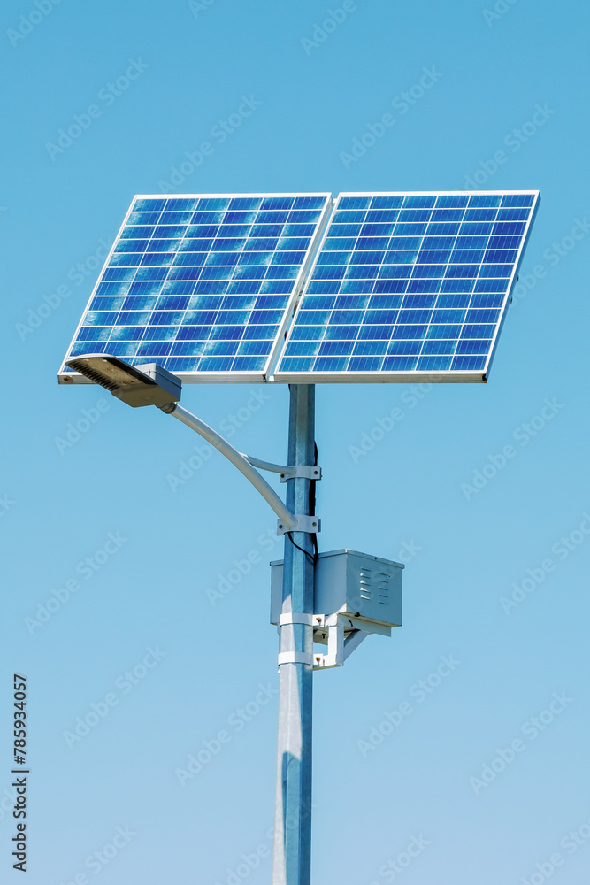 Solar device with street lamp on background of blue sky. Street light powered by solar panel with battery included. Alternative energy from the sun