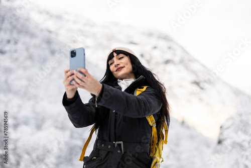 Winter Hiker Capturing Memories with Smartphone in Snowy Mountains