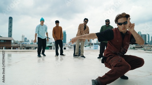 Professional asian street dancer practice B boy dance while multicultural friends at roof top. Young modern dancing group doing hip hop movement. Style,fashion,action. Outdoor sport 2024. Endeavor.