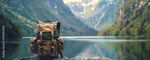Tourist backpack in mountain peaks with lake in background.