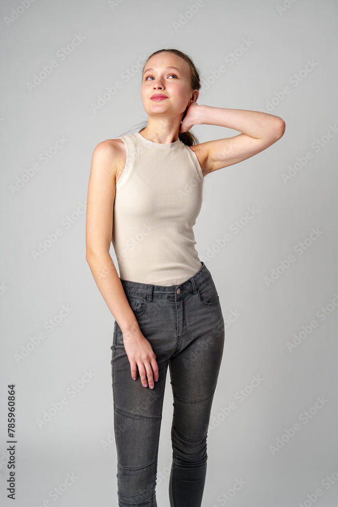 Girl in Beige Tank Top and Grey Jeans on gray background Girl in Beige Tank Top and Grey Jeans on gray background