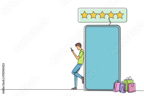 Continuous one line drawing young happy smiling man leaning on giant smartphone while typing on smartphone. Concept of online shop. Review five gold stars. Single line draw design vector illustration