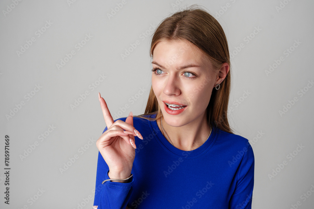 Young Woman Gesturing With Her Finger While Speaking Against a Gray Background Young Woman Gesturing With Her Finger While Speaking Against a Gray Background