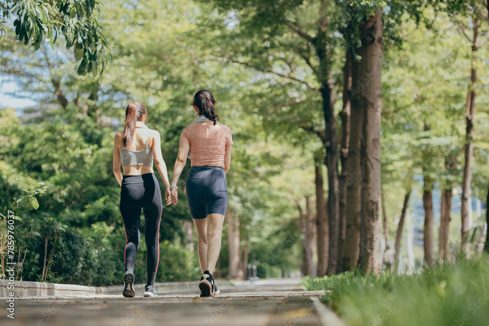 two Asian women engaging in physical activity within an urban park. two Asian women engaging in physical activity within an urban park.