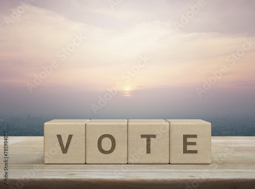 Vote letter on wood block cubes on wooden table over city tower and skyscraper at sunset, vintage style, Election and voting concept
