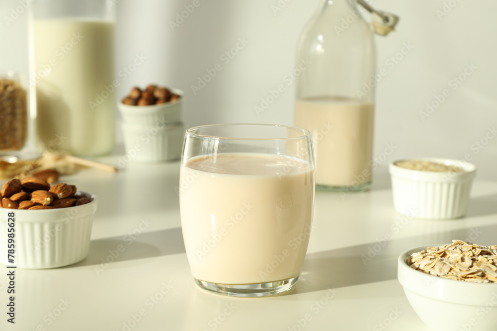 Bottles and glass of alternative milk, nuts and oatmeal on light background, close up