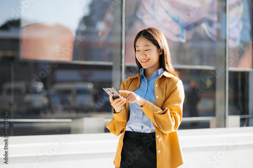 Young Asian business woman leader entrepreneur, professional manager holding digital tablet computer uon the street in big city photo