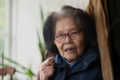 An Asian grandmother in her nineties is engaged in conversation while a relative lovingly puts his arm around her. She is of Okinawan (Ryukyuan) ancestry.