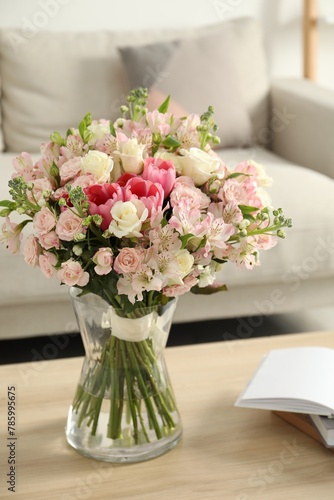 Beautiful bouquet of fresh flowers in vase on wooden table indoors