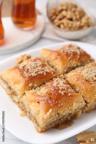 Eastern sweets. Pieces of tasty baklava and tea on white table, closeup