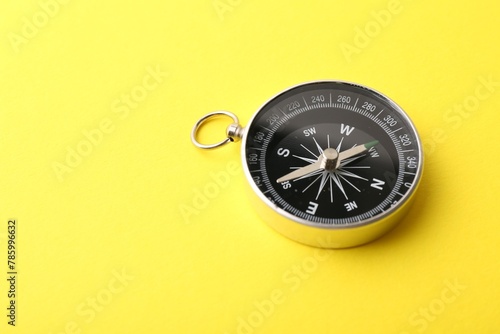 One compass on yellow background, space for text. Tourist equipment