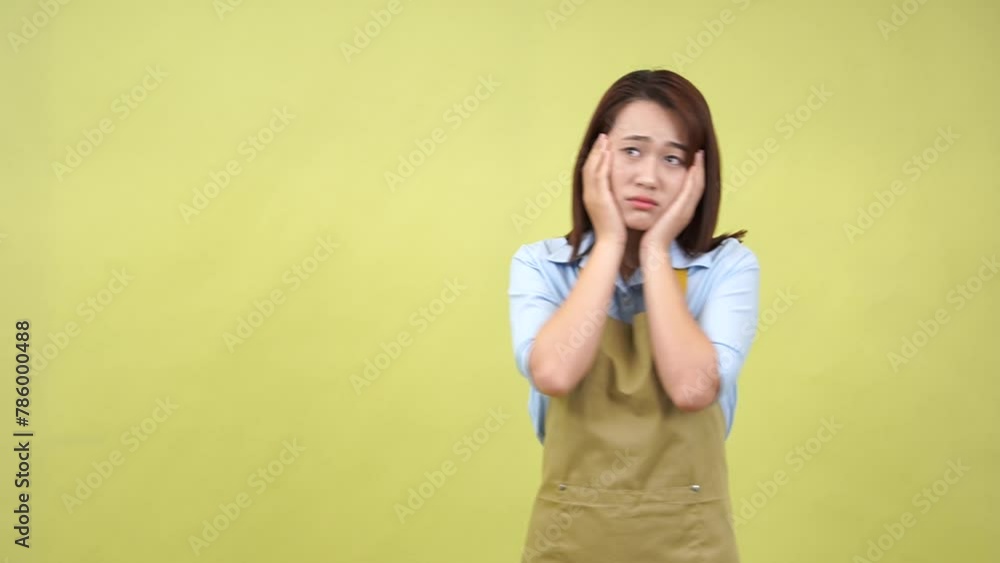 Young Asian woman wearing apron on green background Young Asian woman wearing apron on green background