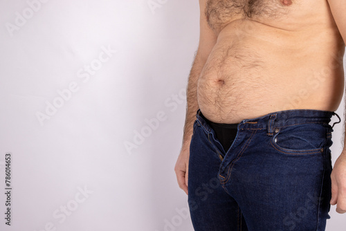Valokuva A middle aged slightly over weight man, trying to put on a pair of jeans but the