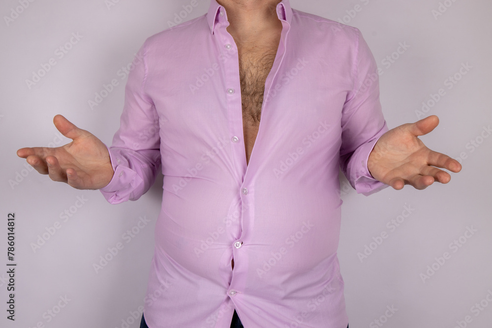A middle aged slightly over weight man in a pink shirt that is now too small due to the man putting on weight and needed to go on a diet, time for a diet concept.