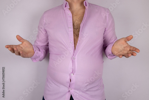 A middle aged slightly over weight man in a pink shirt that is now too small due to the man putting on weight and needed to go on a diet, time for a diet concept.