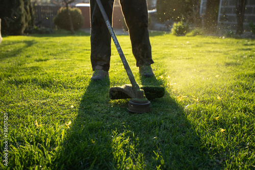 Garden worker with lawn mover. Garden works in spring.