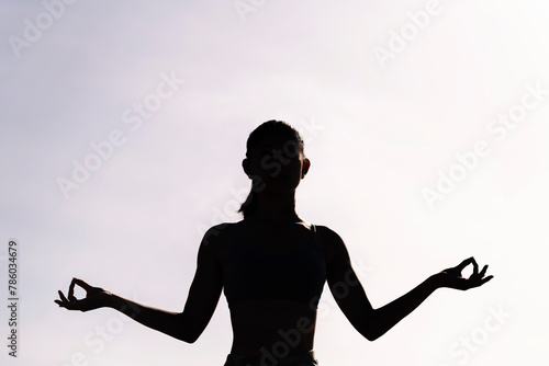 backlight of young woman doing yoga meditation, concept of mental relaxation and healthy lifestyle