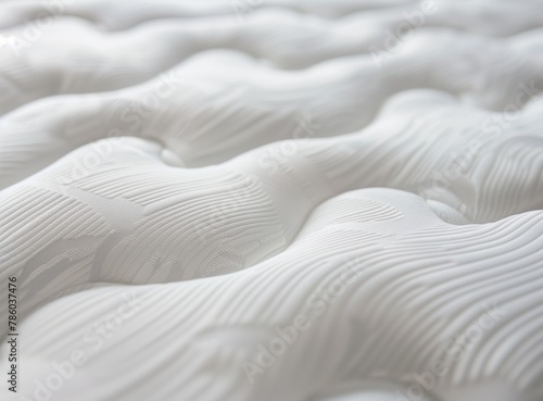 A close-up shot of the texture and pattern on a mattress, highlighting its softness and comfort for sleeping. The background is white to emphasize these details