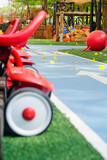 Playground with red toy car on green grass field in public park