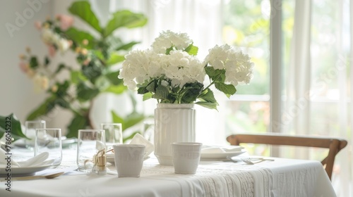 A white tablecloth covers a rectangular table complimented by a vase of flowers enhancing the home s interior design with a natural element