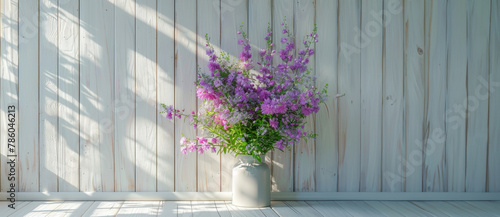A vase of purple flowers sits on a wooden wall