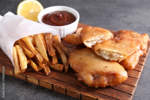 Tasty fish, chips and sauce on grey table, closeup