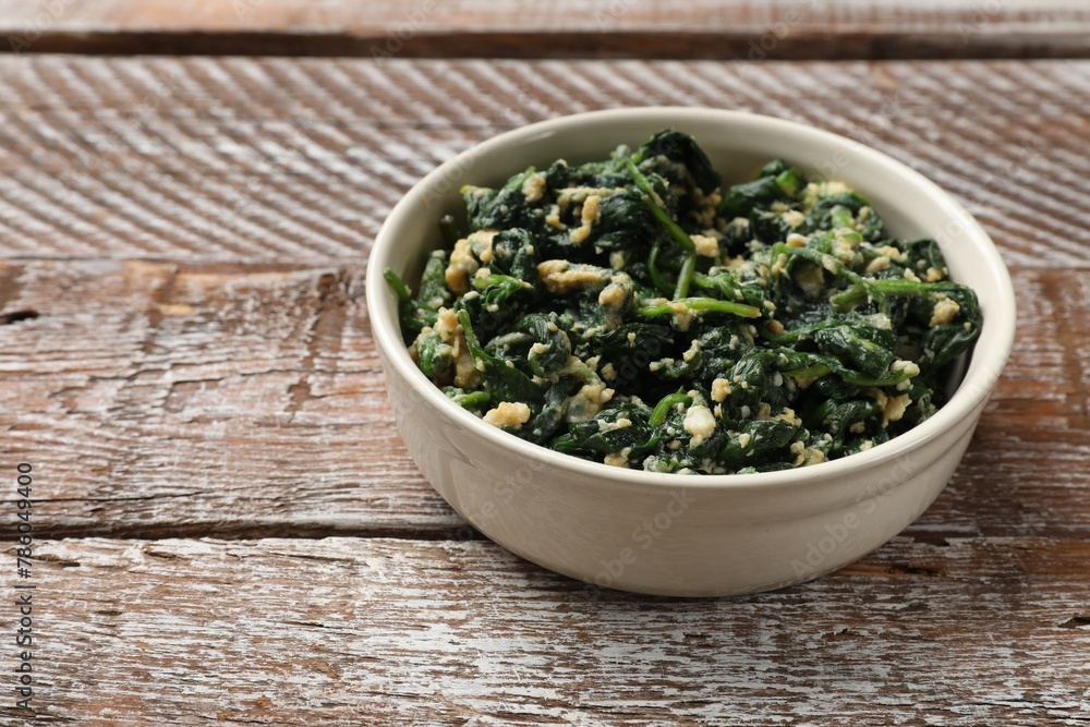 Tasty spinach dip with eggs in bowl on wooden table, space for text Tasty spinach dip with eggs in bowl on wooden table, space for text