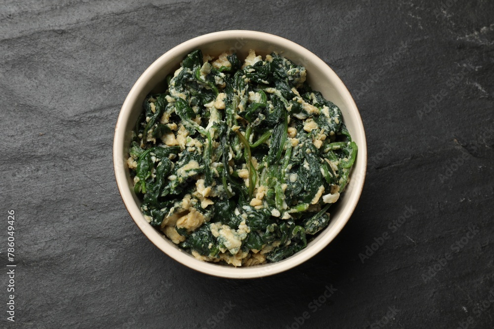 Tasty spinach dip with egg in bowl on black table, top view Tasty spinach dip with egg in bowl on black table, top view