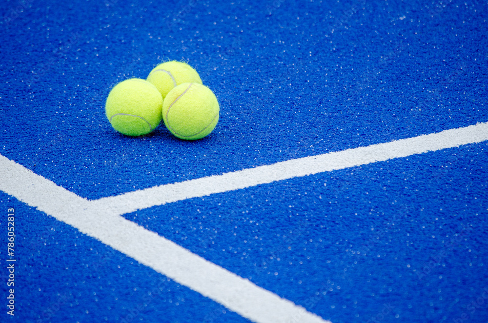 three balls in a blue paddle tennis court