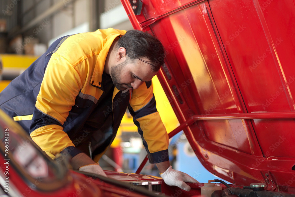 Auto technician examining the broken old car in garage. Auto technician examining the broken old car in garage.