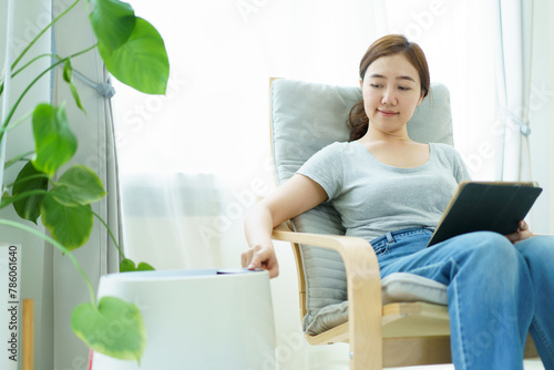 Asian woman using air purifier during living at home.