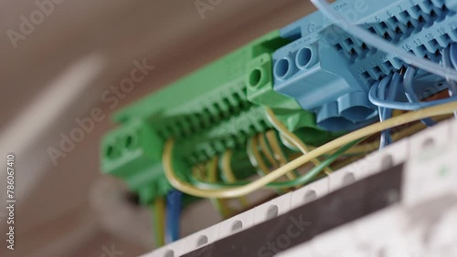 Electrician uses long nose pliers to insert wires into circuit breaker, closeup photo