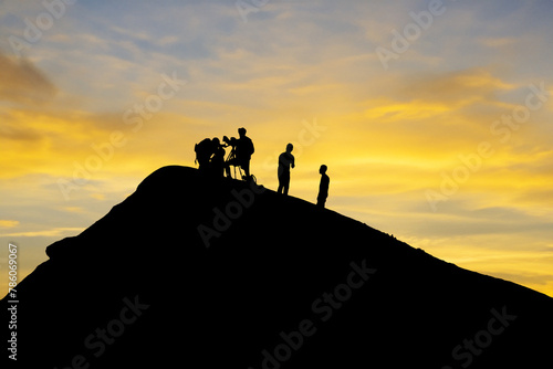 Silhouetted team conducting volcano research during picturesque sunset backdrop