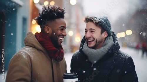 International gay couple strolls enjoying air and warmth of company in park. Gays walk with coffee cups in hands chatting. Boyfriends continue journey with evident love against Christmas decoration