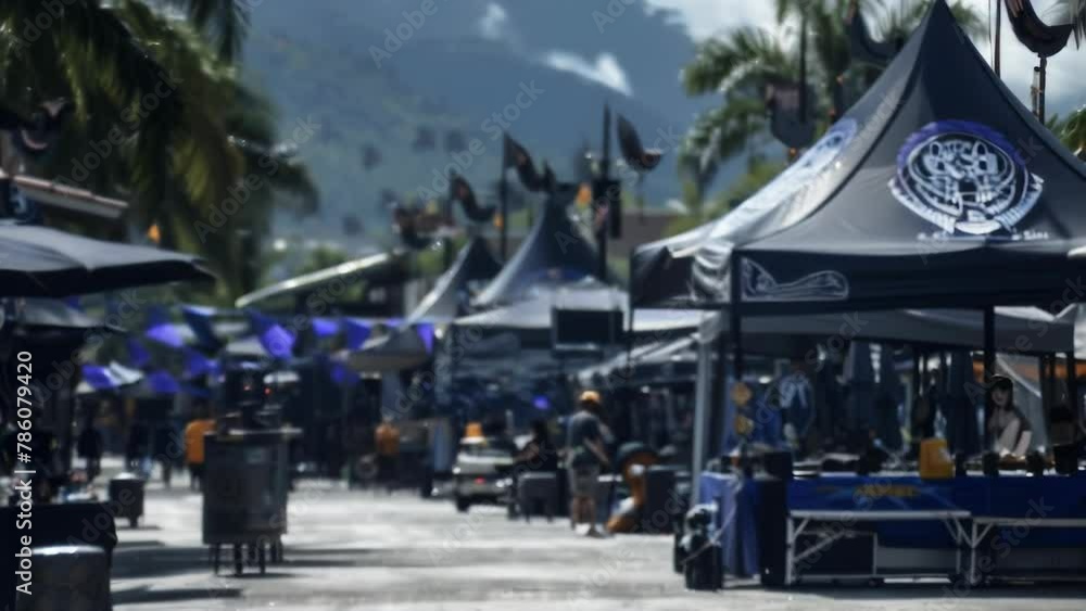 Numerous tents covered in shades of blue fabric are neatly arranged in a wooded outdoor setting. Various wares are displayed inside the tents, bustling with shoppers. Numerous tents covered in shades of blue fabric are neatly arranged in a wooded outdoor setting. Various wares are displayed inside the tents, bustling with shoppers.