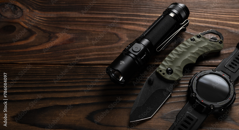 Everyday carry EDC items on wooden background - flashlight, watch and knife. Survival set. Minimal concept Everyday carry EDC items on wooden background - flashlight, watch and knife. Survival set. Minimal concept