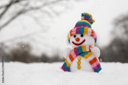 A fabric snowman in hat, scarf, in winter forest. Concept of winter, snow and childhood.