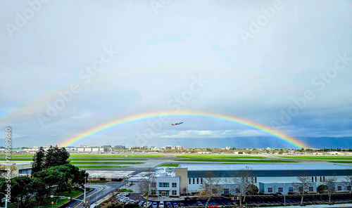 a rainbow appears to overwash the city and a plane photo
