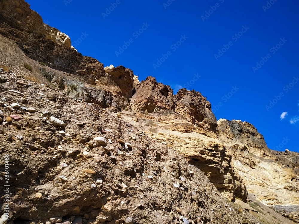 Low-angle shot of the side of a rocky mountain against a clear blue sky
