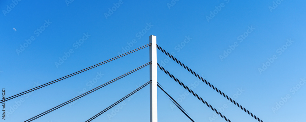 Construction elements of pylon cable-stayed bridge in front of blue sky.