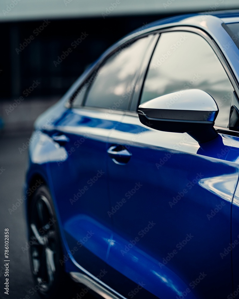 Side shot of a shiny blue sport car mirror and windows with blur background, vertical shot
