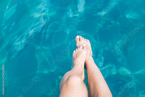 Slender female legs tasting the water. Concept of summer rest and vacation. Background with copy space.