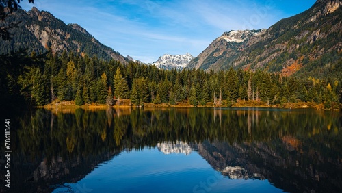 Trees of the dense forest and mountains reflected in the waters of a calm lake in Washington photo