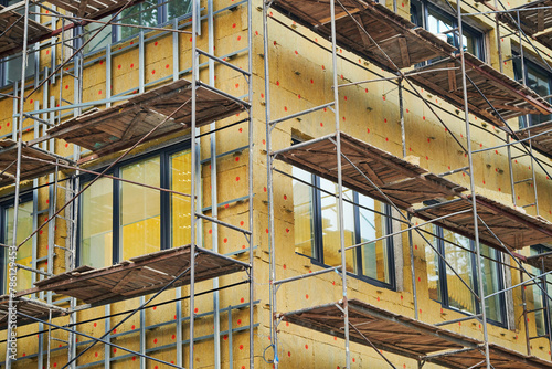 Obraz na płótnie Wall insulation of building wall with mineral wool. Scaffolding, aerial work, insulation of building facade, heat improvement and facing work. Installing thermal protection with scaffolding support w salonie