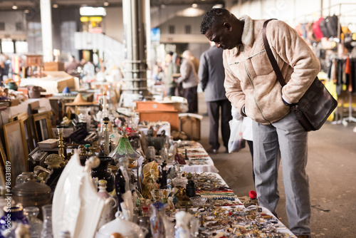 Ordinary Afro-American guy considers things sacond hands on flea market