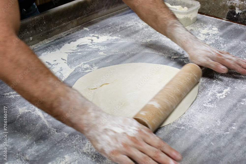 Dough with motion hands with rolling pin on wooden table Dough with motion hands with rolling pin on wooden table